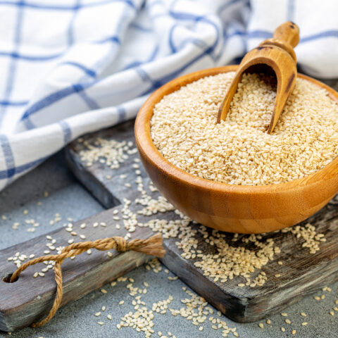 Bowl with sesame seeds and wooden scoop.